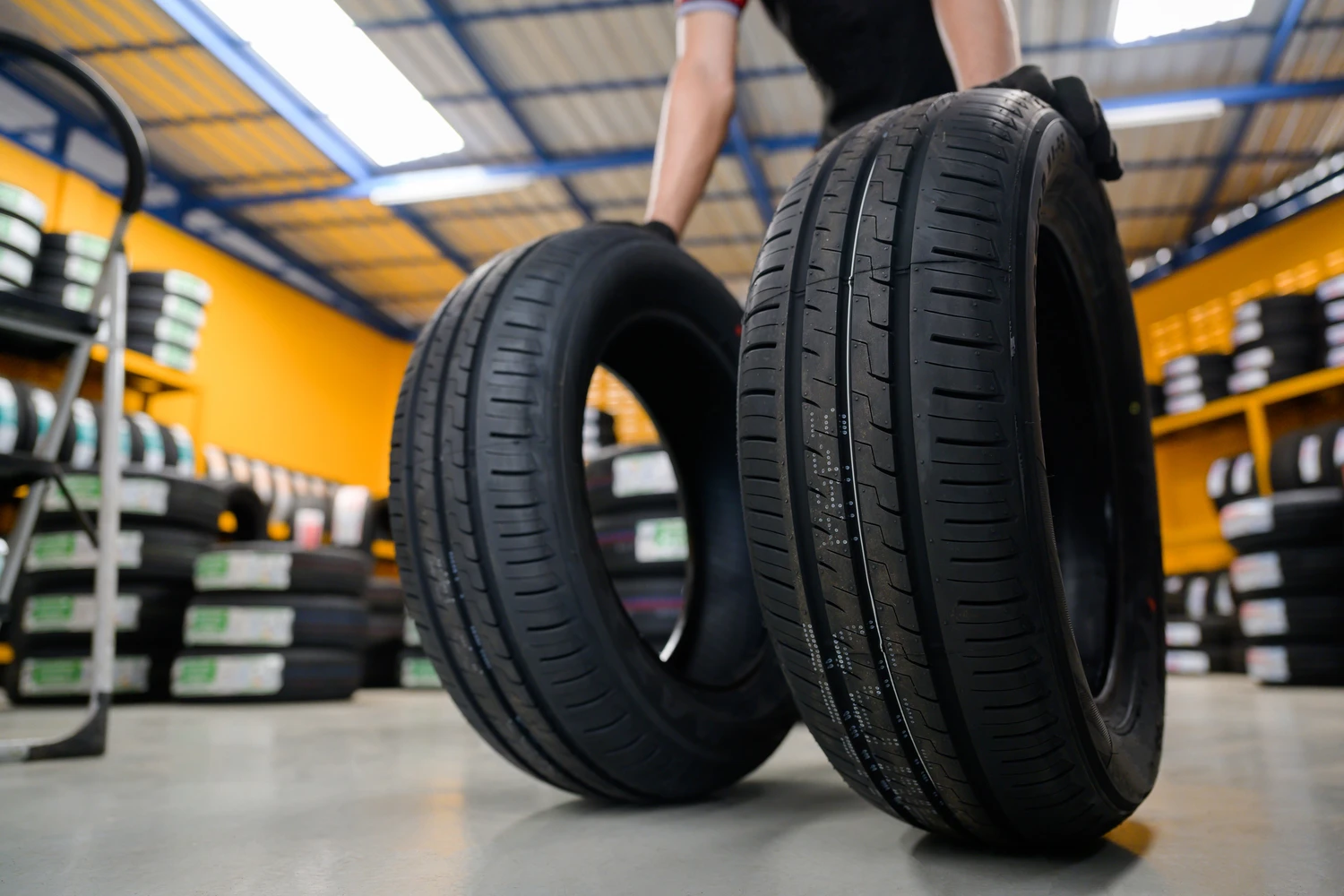 204814762_m In a bustling tire shop, a worker skillfully balances two high-performance tires